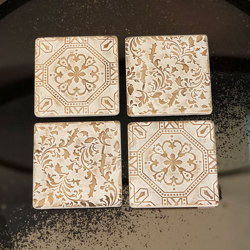 four square tile coaster, two of each pattern. bronze raised detail on cream background