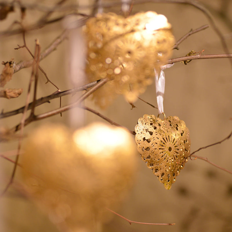 filigree gold hearts hanging on twigs catching the sunlight.