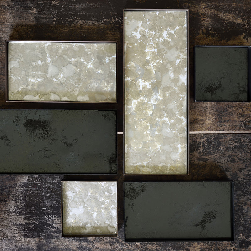 Collection of rectangular trays with marble-like patterns and charcoal finish on a distressed wood background