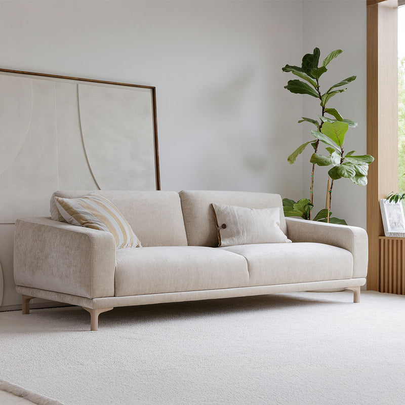 sofa in a minimalistic room with a plant and abstract art.