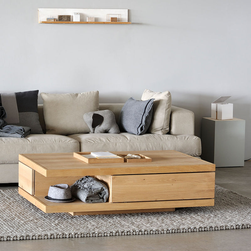 Flat coffee table, showing drawer front and open shelf underneath, set in contemporary living room.