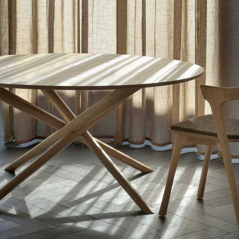 round oak dining table next to a window with light streaming across the table