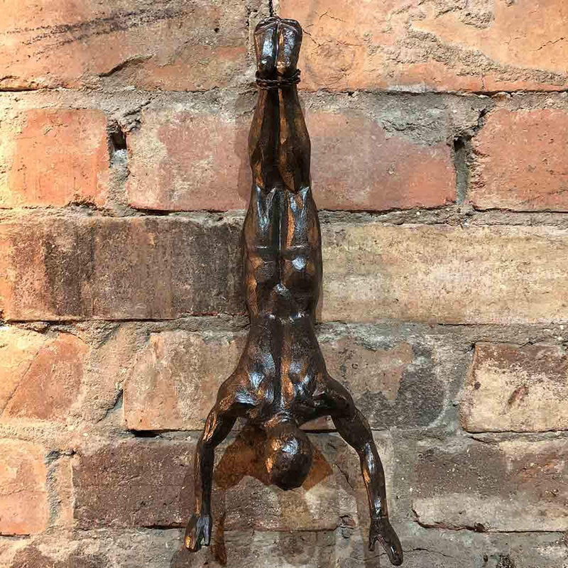 wall mounted sculpture of man diving down, tethered by his feet