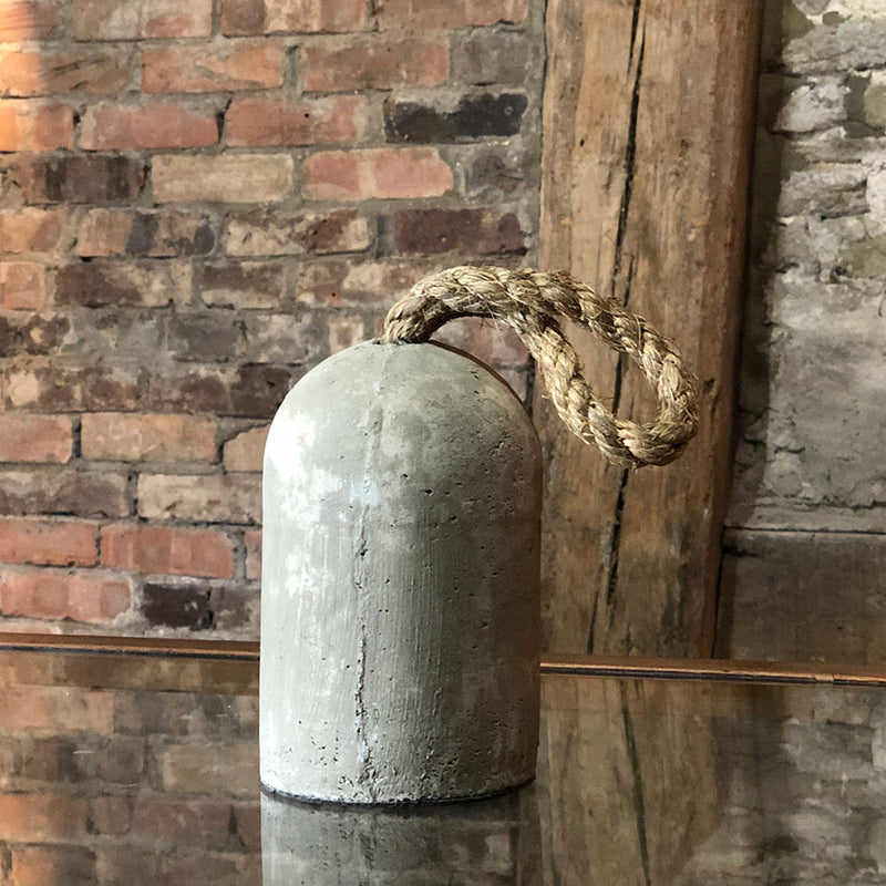 bullet shaped cement doorstop, with rope handle on top.