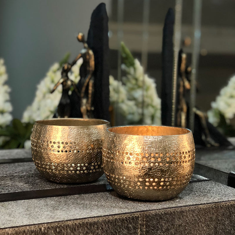 pair of golden votive holders shown on a tabletop.