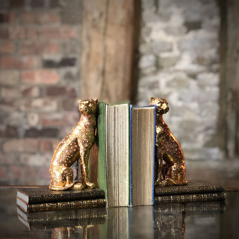 gold cheetah book ends, each animal supporting the books.