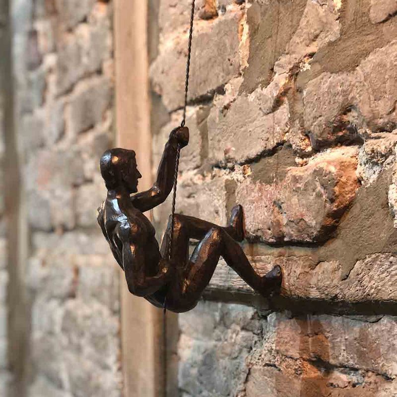 bronze colour climbing nude figure, pulling up a rope.