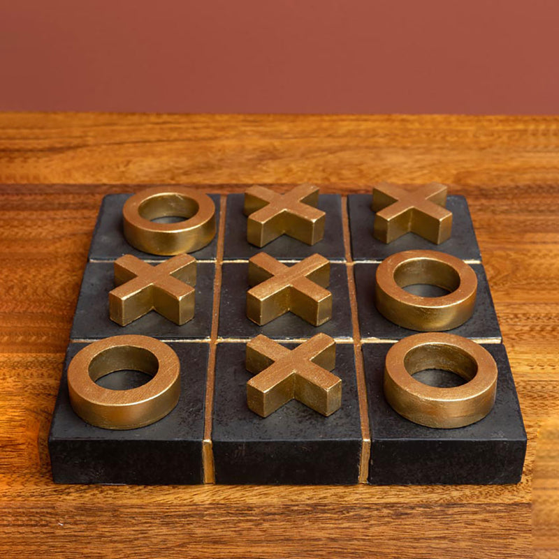 noughts and crosses game with gold pieces on a black stone base viewed low across front