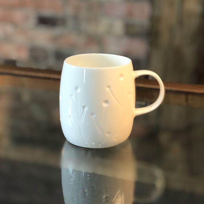 white bone china mug with indednted pattern of growing cotton plants