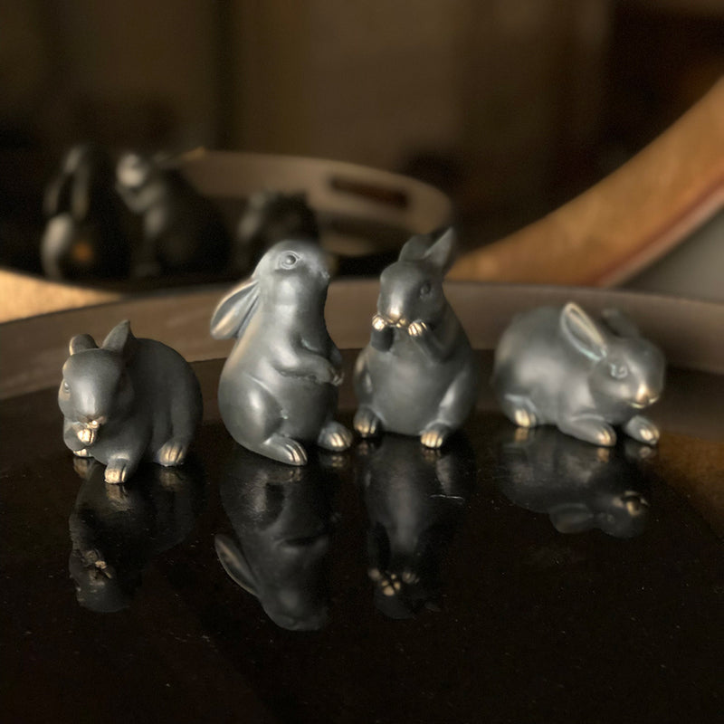 black bunnies with gold tipped feet and noses, hand applied antiqued brass. each rabbit is in different poses.