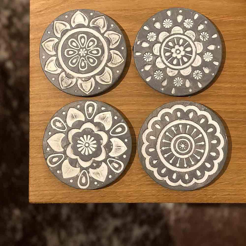 set of four round grey coasters with white circular pattern embossed, view from above