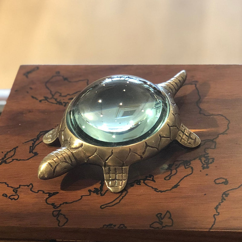 brass turtle stands on the desktop, his shell is a magnifying glass